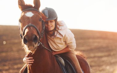 Güneşli bir günde atıyla birlikte tarım alanında koruyucu şapkalı genç bir kadın..