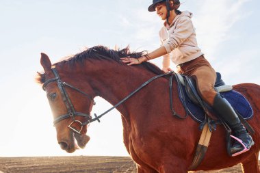 Güneşli bir günde atıyla birlikte tarım alanında koruyucu şapkalı genç bir kadın..