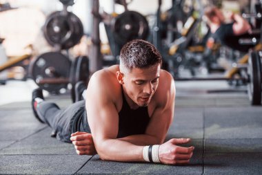 Mola verdim. Siyah elbiseli genç sporcu güçlü adam spor salonunda antrenman yapıyor..