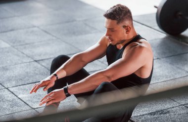 Siyah elbiseli genç sporcu güçlü adam spor salonunda antrenman yapıyor..