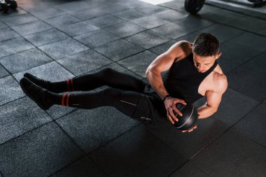 Siyah giysili genç sporcu adam spor salonunda top oynuyor..