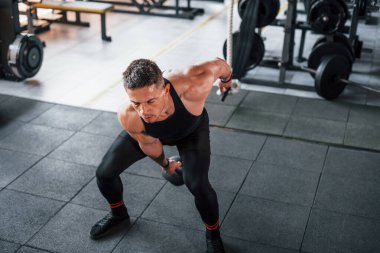 Kilo vermek. Siyah elbiseli genç sporcu güçlü adam spor salonunda antrenman yapıyor..