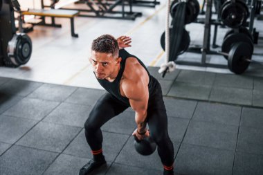 Kilo vermek. Siyah elbiseli genç sporcu güçlü adam spor salonunda antrenman yapıyor..