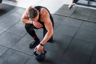 Kilo vermek. Siyah elbiseli genç sporcu güçlü adam spor salonunda antrenman yapıyor..