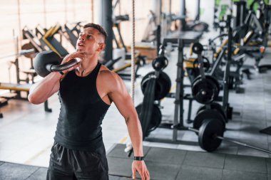 Kilo vermek. Siyah elbiseli genç sporcu güçlü adam spor salonunda antrenman yapıyor..