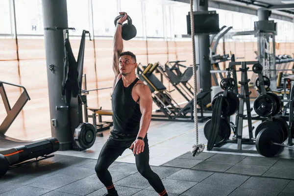 Kilo vermek. Siyah elbiseli genç sporcu güçlü adam spor salonunda antrenman yapıyor..