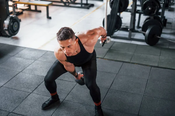 Kilo vermek. Siyah elbiseli genç sporcu güçlü adam spor salonunda antrenman yapıyor..