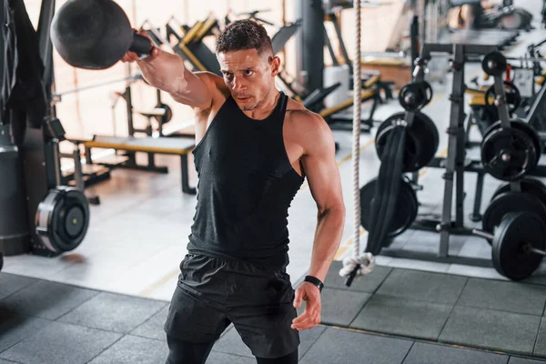 Kilo vermek. Siyah elbiseli genç sporcu güçlü adam spor salonunda antrenman yapıyor..