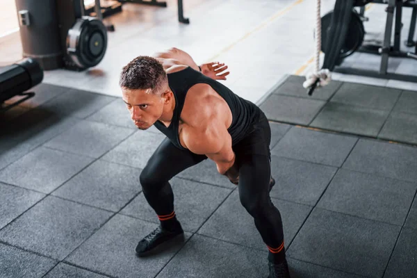Kilo vermek. Siyah elbiseli genç sporcu güçlü adam spor salonunda antrenman yapıyor..