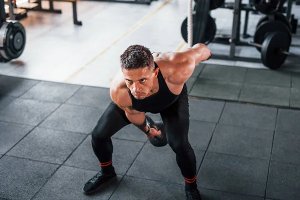 Kilo vermek. Siyah elbiseli genç sporcu güçlü adam spor salonunda antrenman yapıyor..