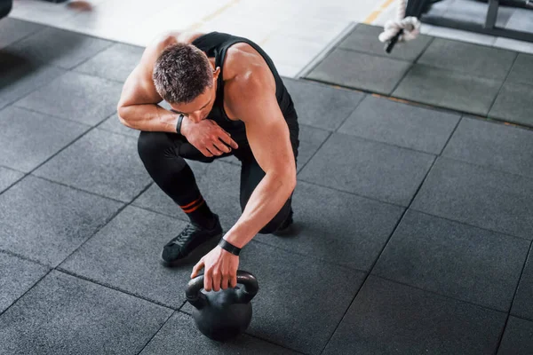 Kilo vermek. Siyah elbiseli genç sporcu güçlü adam spor salonunda antrenman yapıyor..