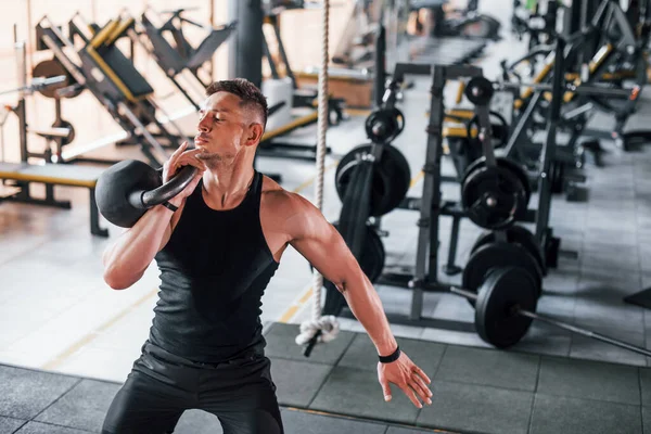 Kilo vermek. Siyah elbiseli genç sporcu güçlü adam spor salonunda antrenman yapıyor..