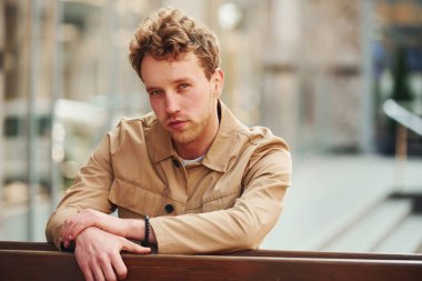 Şehrin dışındaki ahşap çitlere yaslanan resmi klas elbiseli zarif genç adam..