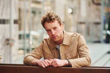 Şehrin dışındaki ahşap çitlere yaslanan resmi klas elbiseli zarif genç adam..