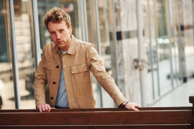 Şehrin dışındaki ahşap çitlere yaslanan resmi klas elbiseli zarif genç adam..