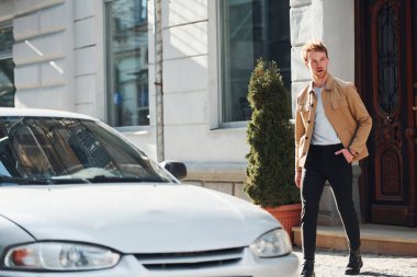 Walks to his car. Elegant young man in formal classy clothes outdoors in the city.