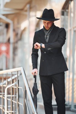 Siyah şapkalı, açık havada şemsiyesi olan zarif bir genç..