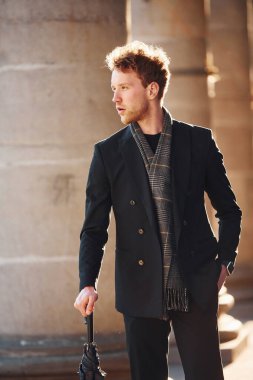 Şemsiye tutuyorum. Şehrin dışında şık kıyafetler içinde zarif bir genç adam..