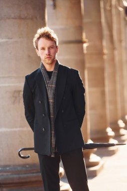 Şemsiye tutuyorum. Şehrin dışında şık kıyafetler içinde zarif bir genç adam..