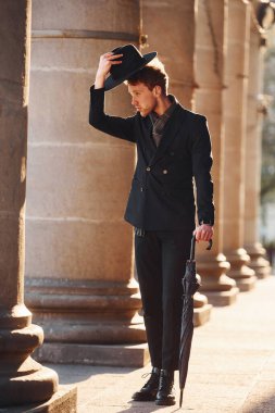 Siyah şapkalı, elinde şemsiyesi olan şık bir genç adam..