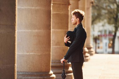 Siyah şapkalı, elinde şemsiyesi olan şık bir genç adam..