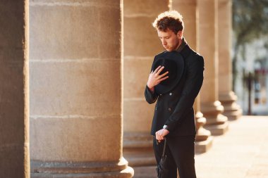 Siyah şapkalı, elinde şemsiyesi olan şık bir genç adam..