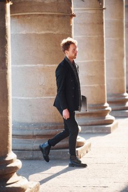 Ellerinde dizüstü bilgisayarla. Gözlüklü zarif genç adam şehrin dışında şık kıyafetler giyiyor..