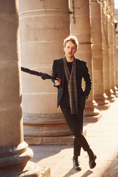 Şemsiye tutuyorum. Şehrin dışında şık kıyafetler içinde zarif bir genç adam..