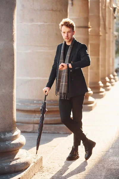 Şemsiye tutuyorum. Şehrin dışında şık kıyafetler içinde zarif bir genç adam..