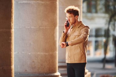 Telefonla konuşuyorum. Şehrin dışında şık kıyafetler içinde zarif bir genç adam..