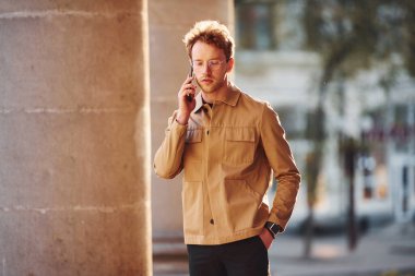 Telefonla konuşuyorum. Şehrin dışında şık kıyafetler içinde zarif bir genç adam..