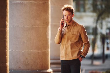 Telefonla konuşuyorum. Şehrin dışında şık kıyafetler içinde zarif bir genç adam..