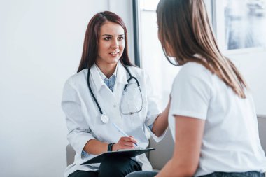 Oturup konuşmak. Genç bayan, modern klinikteki kadın doktoru ziyaret ediyor..