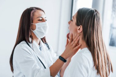 Lenf düğümlerini ve boğazını kontrol ediyorum. Genç bayan, modern klinikteki kadın doktoru ziyaret ediyor..