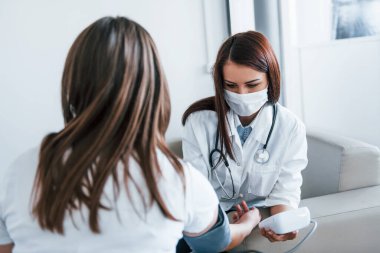 Kan basıncını ölçüyorum. Genç bayan, modern klinikteki kadın doktoru ziyaret ediyor..