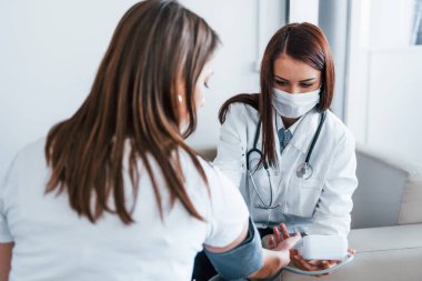 Kan basıncını ölçüyorum. Genç bayan, modern klinikteki kadın doktoru ziyaret ediyor..