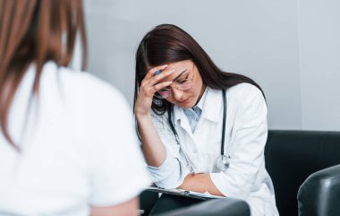 Oturup konuşmak. Genç bayan, modern klinikteki kadın doktoru ziyaret ediyor..