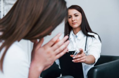 Doktor ağlayan hastaya ilaç veriyor. Genç bayan, modern klinikteki kadın doktoru ziyaret ediyor..