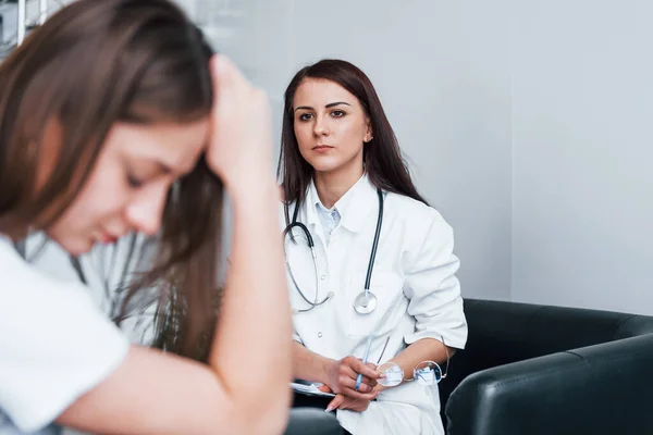 Girl have mental breakdown and crying. Young woman have a visit with female doctor in modern clinic.