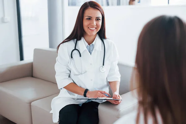 Friendly doctor listening to the patient. Young woman have a visit with female doctor in modern clinic.