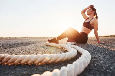 Spor kıyafetli bir kadın akşam vakti yolda düğümlerle oturuyor..