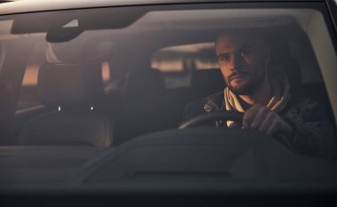 Moda giysileri içinde arabasıyla gezen yakışıklı, tıraşsız bir adamın ön görüntüsü..