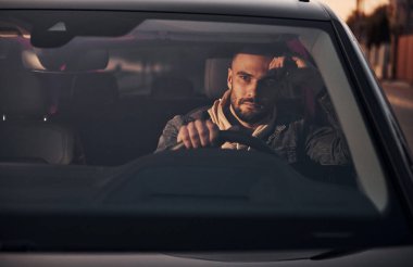 Moda giysileri içinde arabasıyla gezen yakışıklı, tıraşsız bir adamın ön görüntüsü..