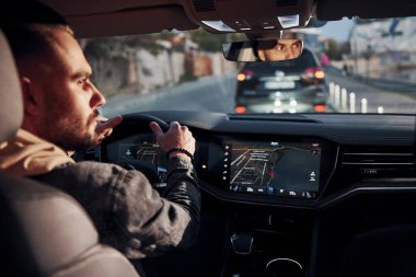 Arabasına binen şık giyinmiş, tıraşsız, yakışıklı adamın arka manzarası..