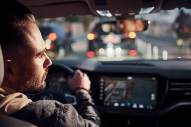 Arabasına binen şık giyinmiş, tıraşsız, yakışıklı adamın arka manzarası..