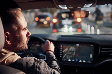 Arabasına binen şık giyinmiş, tıraşsız, yakışıklı adamın arka manzarası..