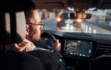 Arabasına binen şık giyinmiş, tıraşsız, yakışıklı adamın arka manzarası..