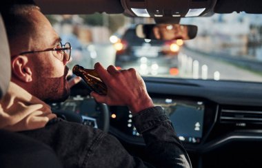 İçkili araba kullanma. Arabasının içinde şık giyinmiş, tıraşsız, yakışıklı bir adam..