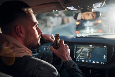 İçkili araba kullanma. Arabasının içinde şık giyinmiş, tıraşsız, yakışıklı bir adam..