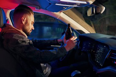 Siyah ve kırmızı polis ışıkları. İçkili araba kullanma. Arabasının içinde şık giyinmiş, tıraşsız yakışıklı bir adam..